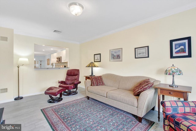 living room featuring baseboards, wood finished floors, visible vents, and crown molding