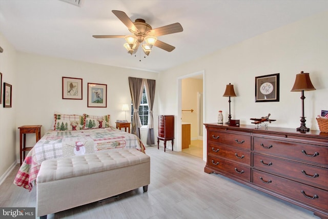 bedroom featuring a ceiling fan, baseboards, light wood finished floors, and ensuite bathroom