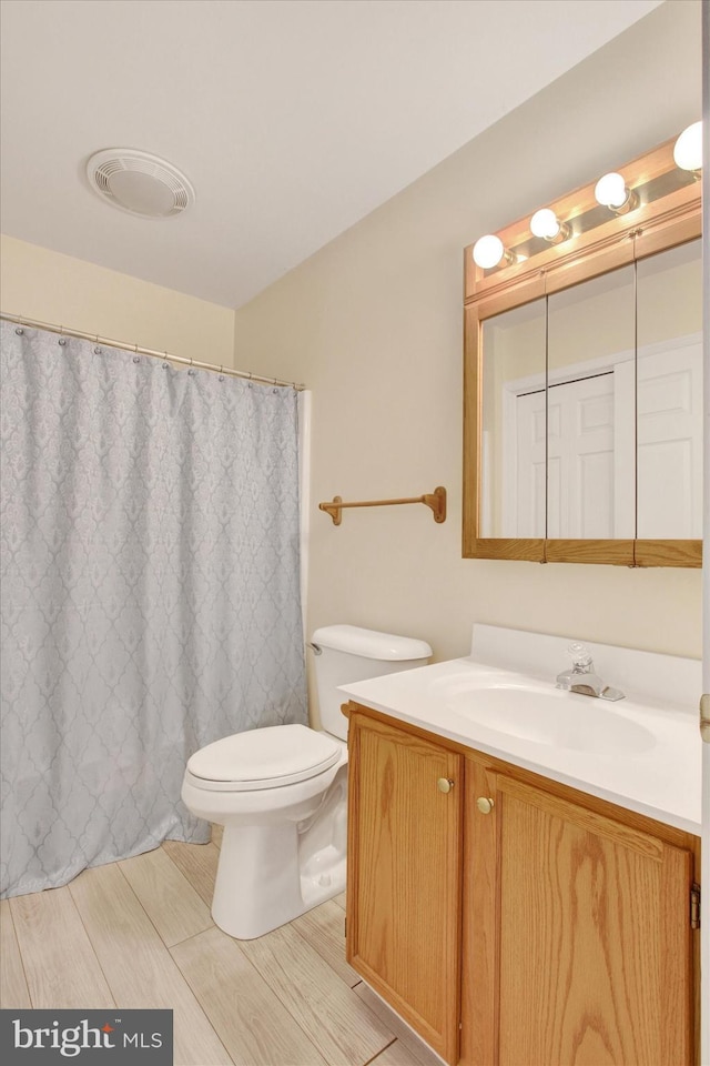 bathroom with toilet, curtained shower, vanity, and visible vents