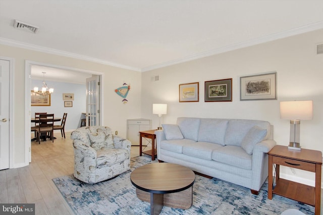 living area featuring crown molding, visible vents, a chandelier, and wood finished floors