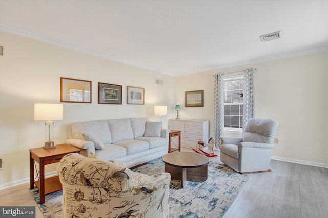 living room with light wood-type flooring, visible vents, and crown molding