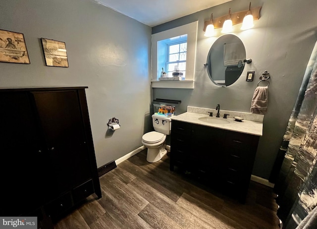 bathroom featuring toilet, vanity, baseboards, and wood finished floors