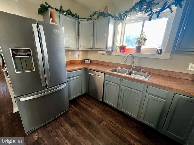 kitchen with appliances with stainless steel finishes, light countertops, dark wood-type flooring, and a sink