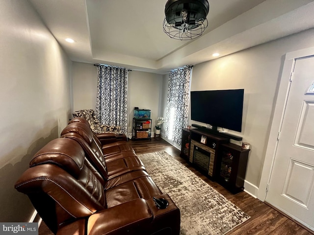 living area featuring dark wood-style floors, recessed lighting, a raised ceiling, and baseboards