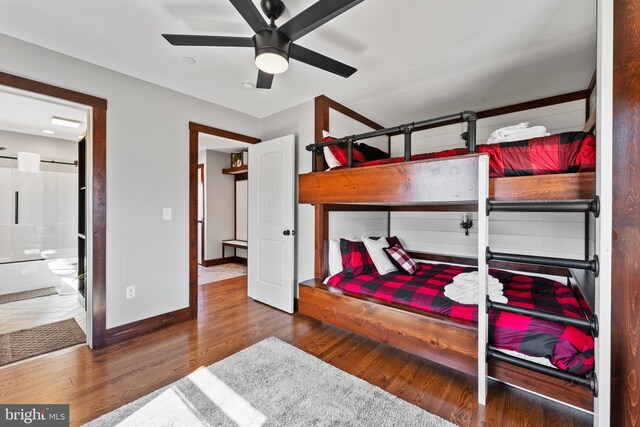 bedroom with baseboards, a ceiling fan, wood finished floors, and ensuite bathroom