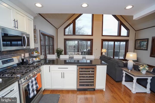 kitchen with stainless steel appliances, wine cooler, lofted ceiling, and a peninsula