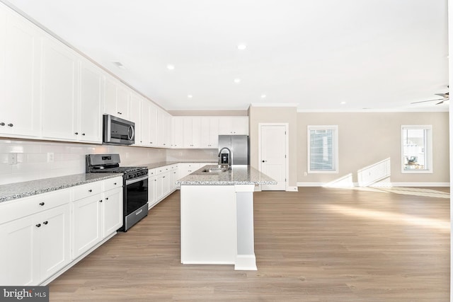 kitchen with appliances with stainless steel finishes, open floor plan, a sink, and tasteful backsplash