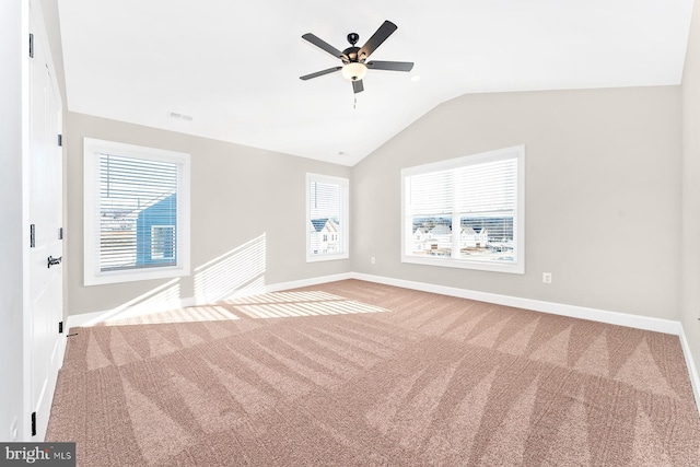 carpeted empty room with a healthy amount of sunlight, baseboards, visible vents, and vaulted ceiling