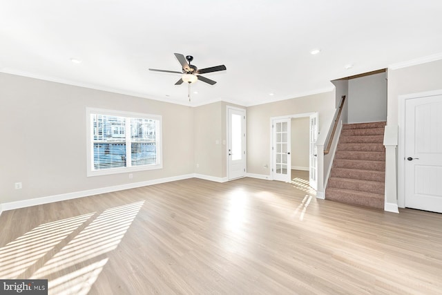 unfurnished living room featuring crown molding, light wood-style flooring, baseboards, and stairs