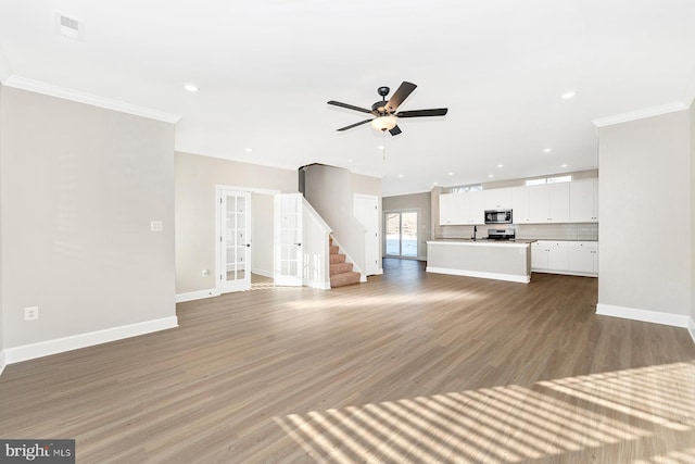 unfurnished living room with french doors, visible vents, ornamental molding, light wood-style floors, and baseboards