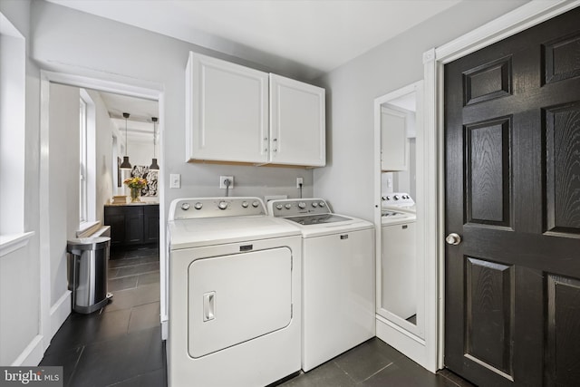 washroom with cabinet space, washing machine and dryer, and dark tile patterned flooring