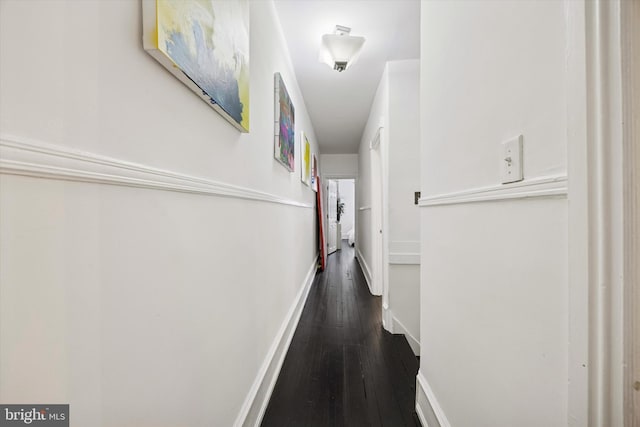 hallway with baseboards and dark wood-type flooring