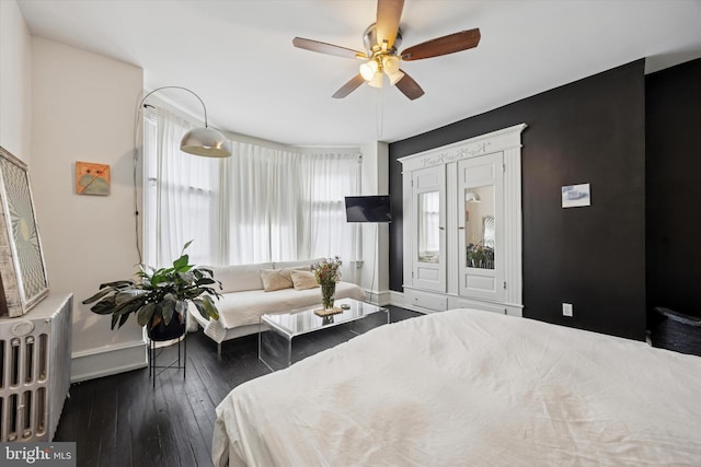 bedroom featuring a ceiling fan, radiator heating unit, baseboards, and hardwood / wood-style floors