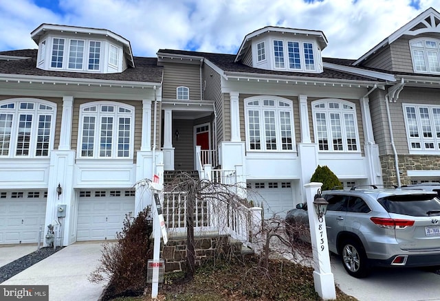 multi unit property with driveway, a shingled roof, a garage, and stairway