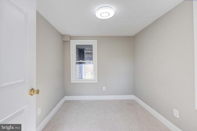 spare room featuring light colored carpet and baseboards