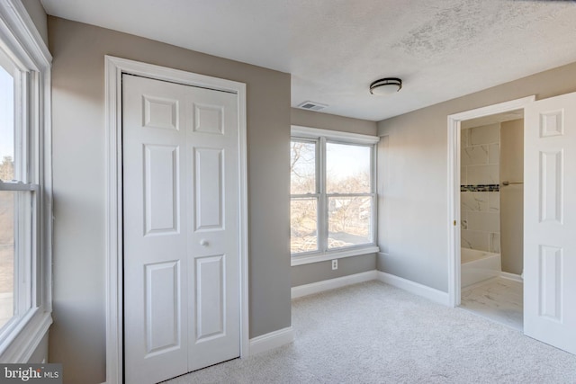 unfurnished bedroom featuring visible vents, baseboards, connected bathroom, carpet, and a textured ceiling