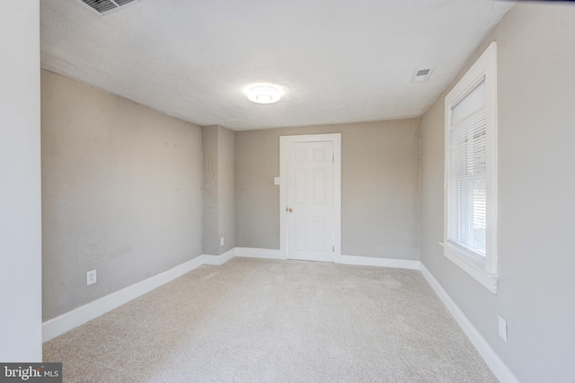 unfurnished room featuring carpet floors, visible vents, a textured ceiling, and baseboards