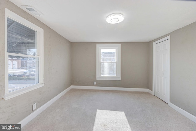 carpeted spare room featuring baseboards and visible vents