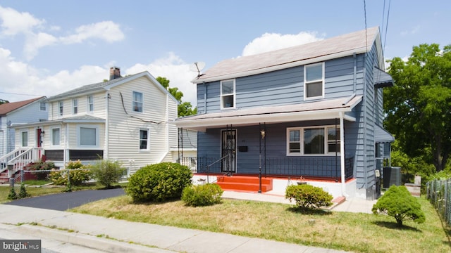 view of front of home featuring cooling unit, covered porch, fence, and a front lawn