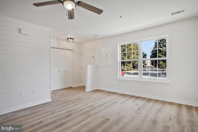 empty room with visible vents, light wood-style flooring, and baseboards