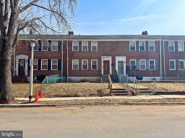 view of property with brick siding, a chimney, and fence