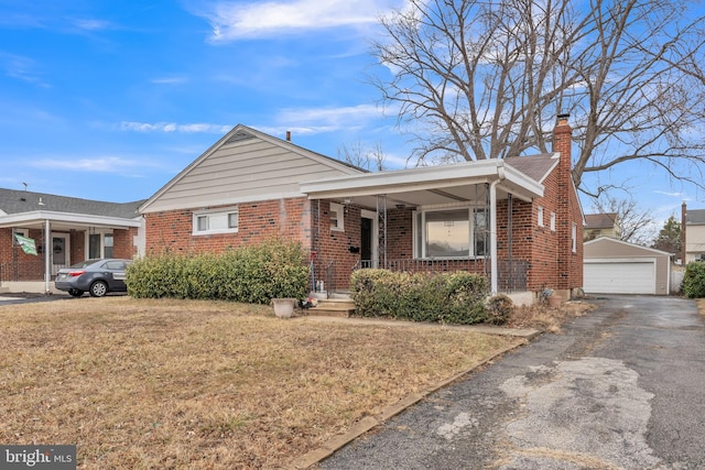 bungalow with brick siding, covered porch, a front yard, a garage, and an outdoor structure