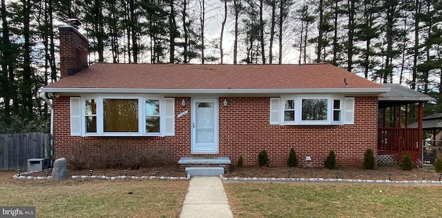 bungalow-style house featuring a chimney, fence, and brick siding