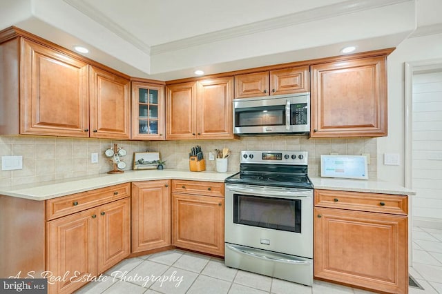 kitchen featuring light tile patterned floors, stainless steel appliances, ornamental molding, and light countertops