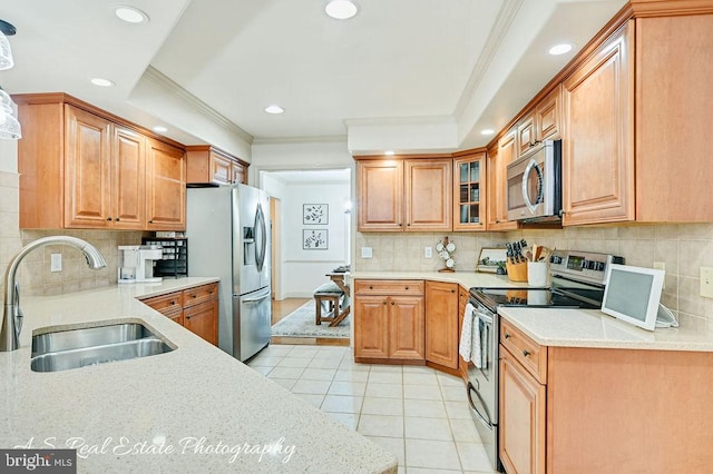 kitchen with light tile patterned floors, stainless steel appliances, a sink, light stone countertops, and crown molding