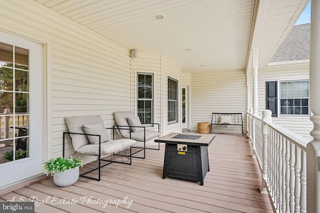 wooden deck featuring covered porch and an outdoor fire pit