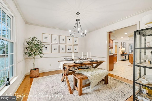 dining room with a chandelier, light wood-style floors, baseboards, and crown molding