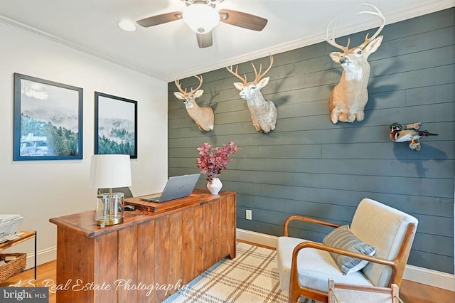 home office featuring light wood finished floors, baseboards, ornamental molding, and a ceiling fan