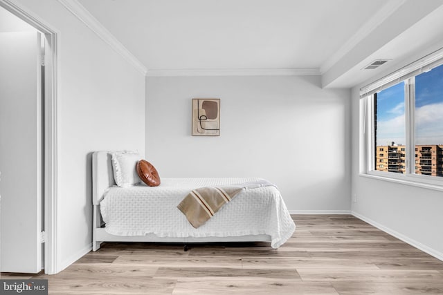 bedroom featuring ornamental molding, visible vents, baseboards, and wood finished floors