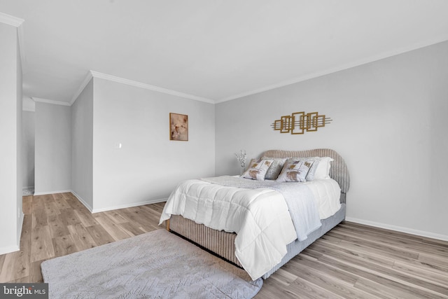 bedroom with crown molding, baseboards, and wood finished floors