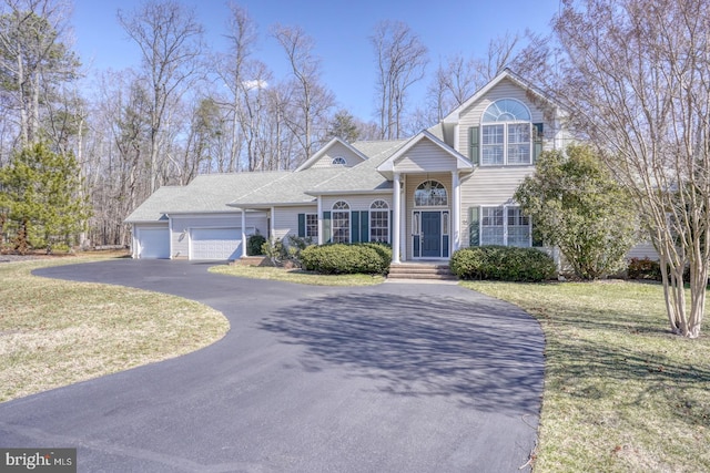 view of front of property featuring a garage, driveway, a front lawn, and roof with shingles