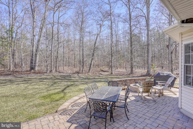 view of patio featuring a forest view, outdoor dining area, and grilling area