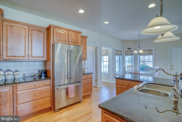 kitchen with recessed lighting, a sink, high end fridge, backsplash, and light wood finished floors