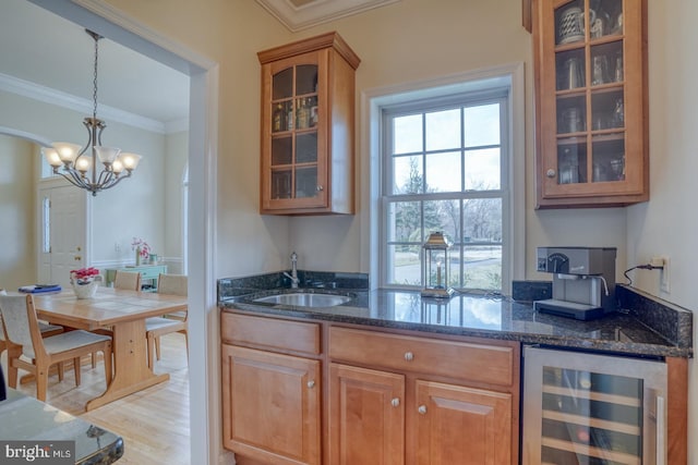 kitchen featuring wine cooler, crown molding, glass insert cabinets, a sink, and dark stone countertops