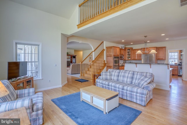 living area featuring light wood finished floors, recessed lighting, visible vents, stairway, and baseboards