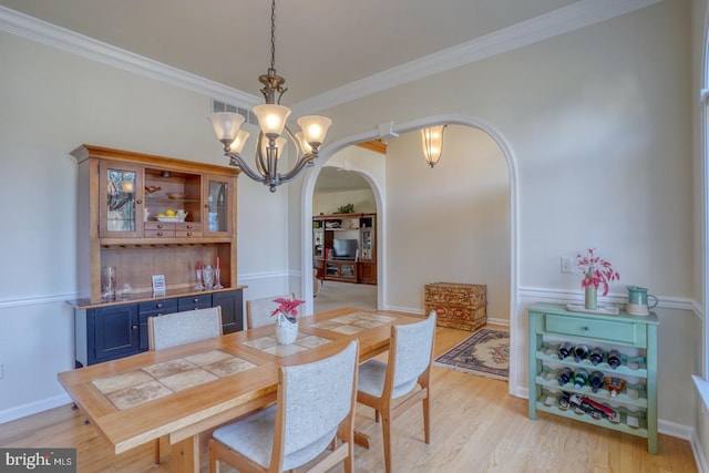 dining space with visible vents, arched walkways, an inviting chandelier, crown molding, and light wood-type flooring