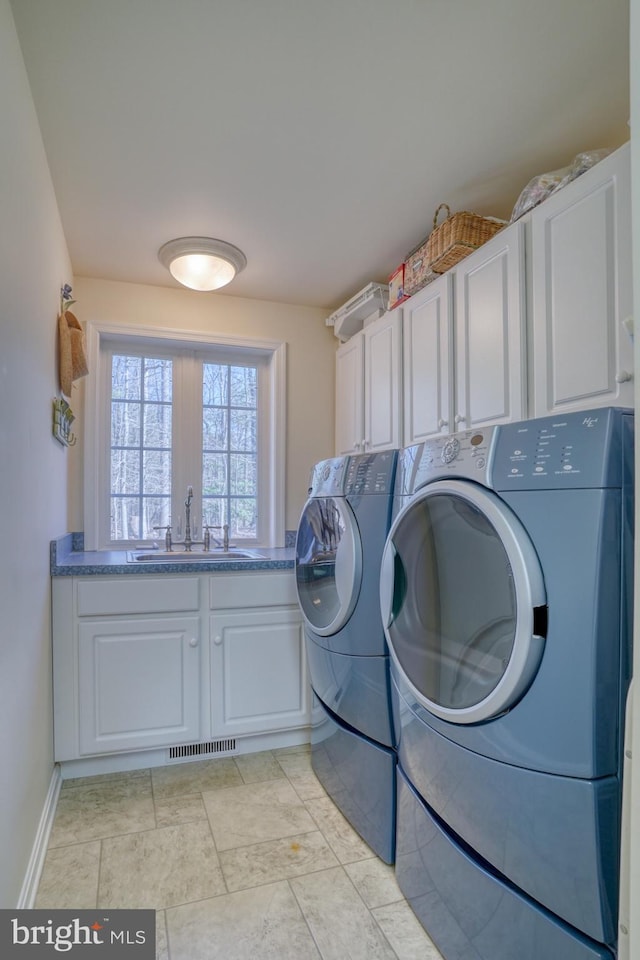 laundry room featuring cabinet space, visible vents, baseboards, washer and dryer, and a sink