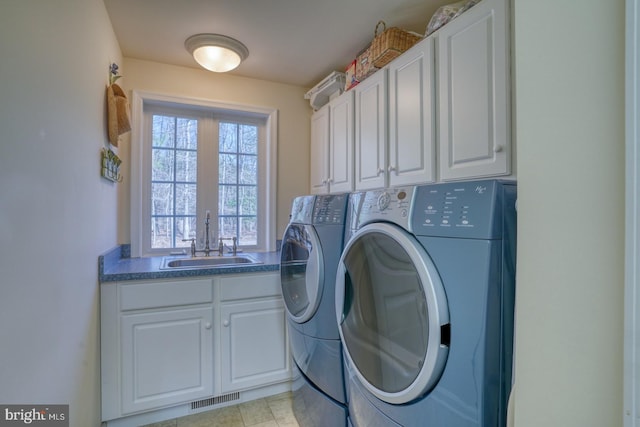 laundry room featuring cabinet space, visible vents, separate washer and dryer, and a sink