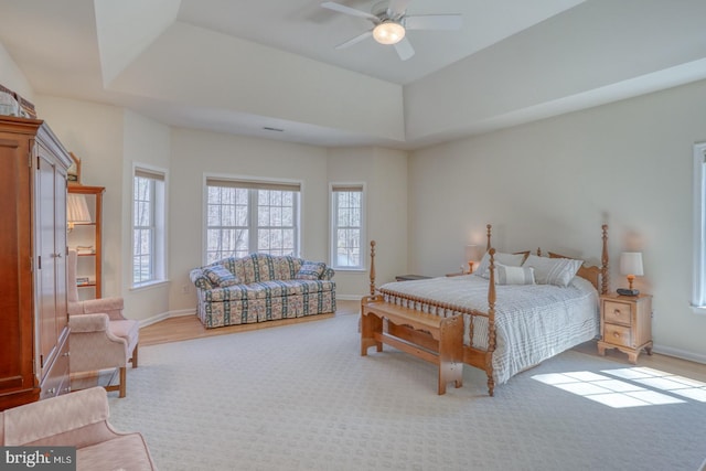 bedroom with multiple windows, a raised ceiling, and baseboards