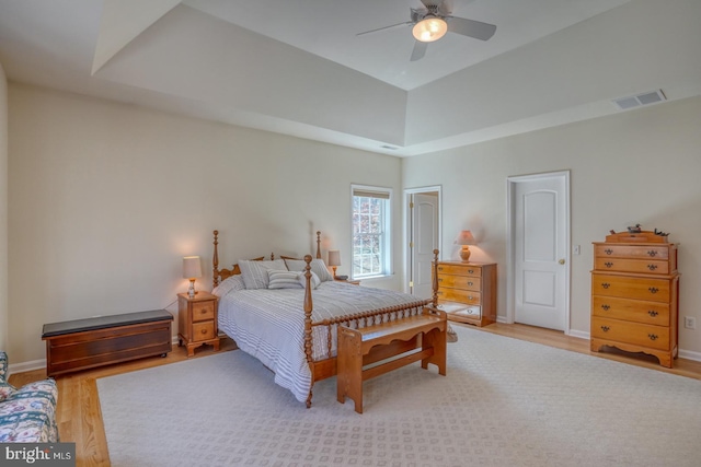 bedroom with a ceiling fan, visible vents, baseboards, and wood finished floors