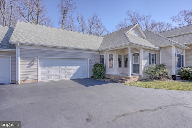 view of front of house with central AC unit, driveway, a shingled roof, and an attached garage