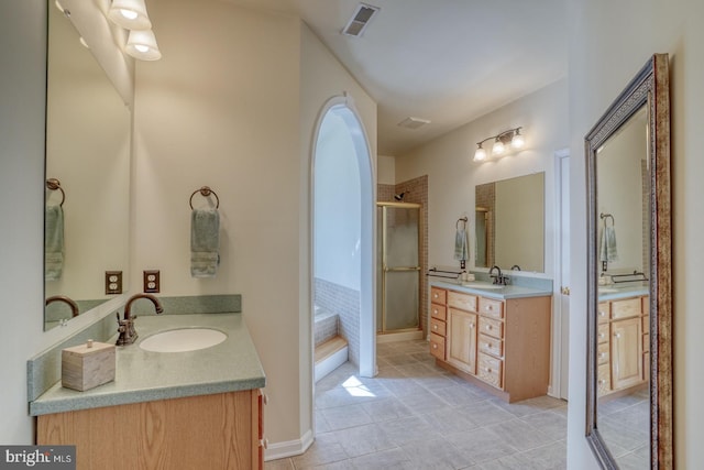 bathroom featuring two vanities, a stall shower, visible vents, and a sink