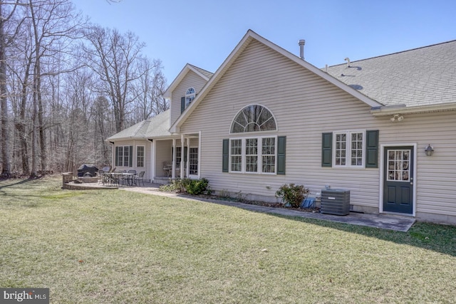 back of house featuring a patio area, a lawn, and roof with shingles