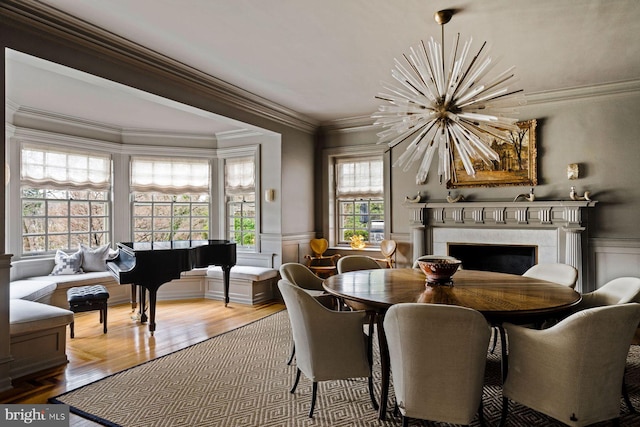 dining area featuring a chandelier, ornamental molding, a premium fireplace, and wainscoting