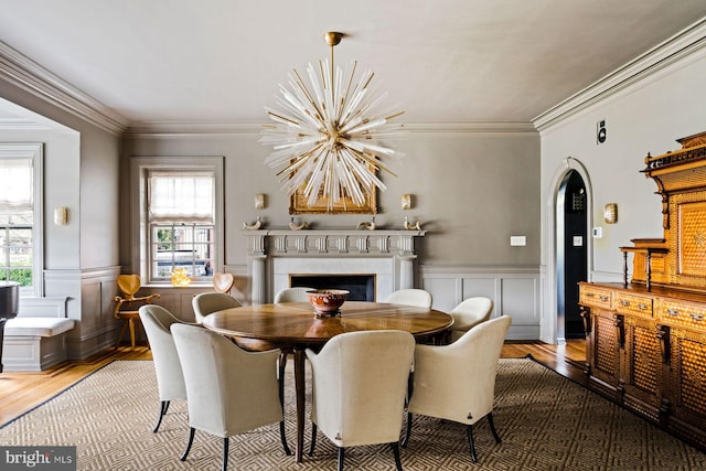 dining area featuring a chandelier, a wainscoted wall, a fireplace, and wood finished floors