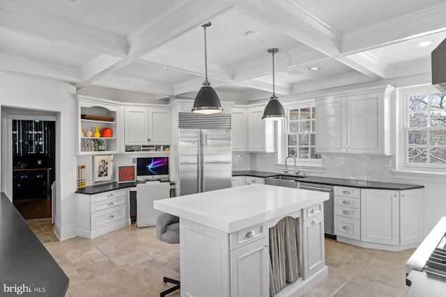 kitchen with stainless steel appliances, a sink, built in desk, and beamed ceiling